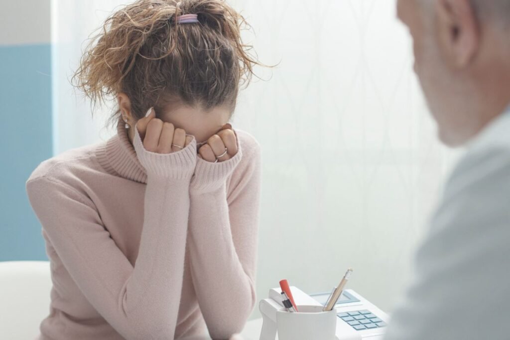 mulher com anorexia com a mão no rosto em frente ao médicomédico